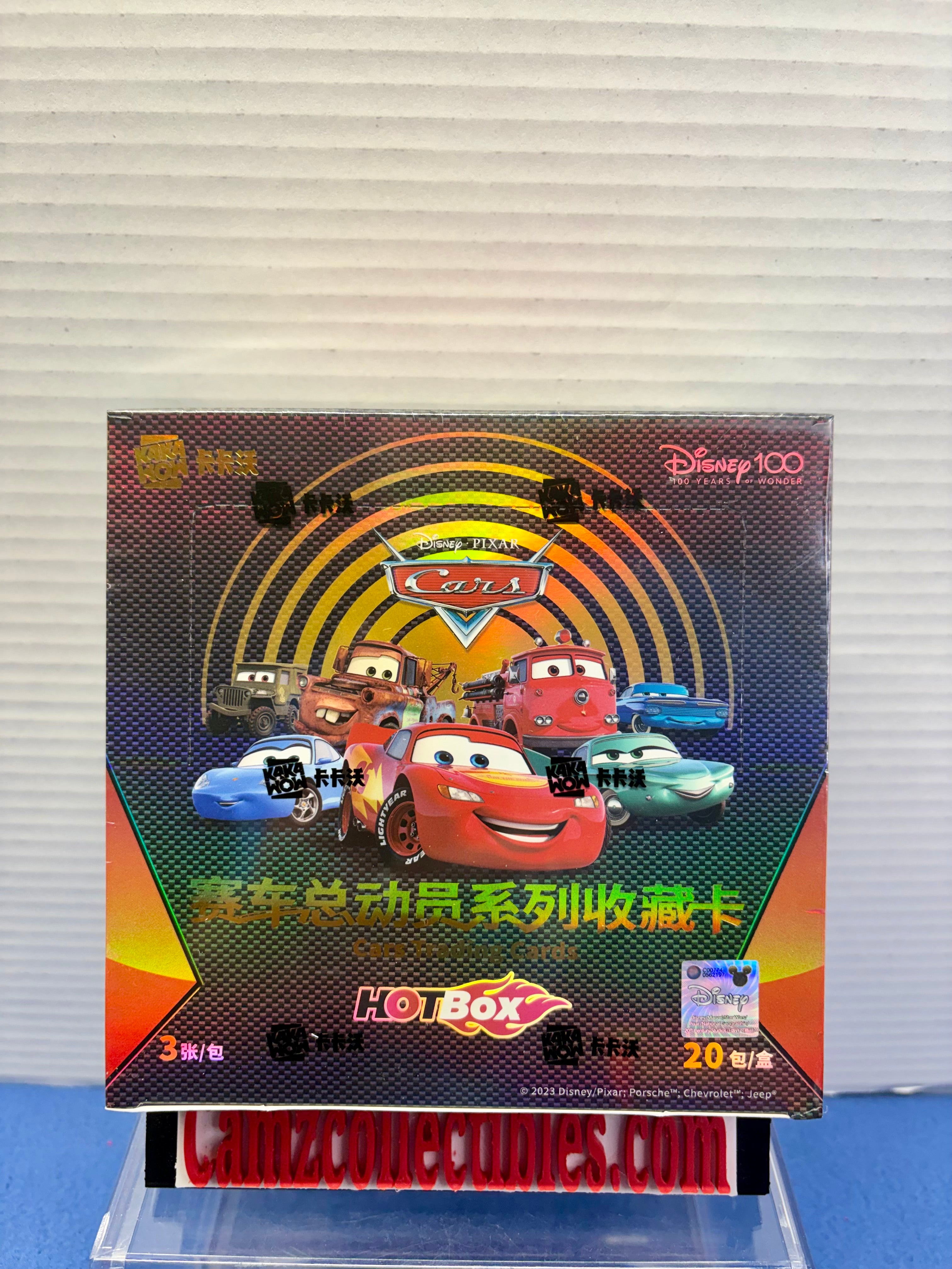 A Disney Cars Hot Box collectible card pack box displayed on a clear stand against a white ribbed wall background. The packaging features Lightning McQueen and other Disney Cars characters with Chinese text.