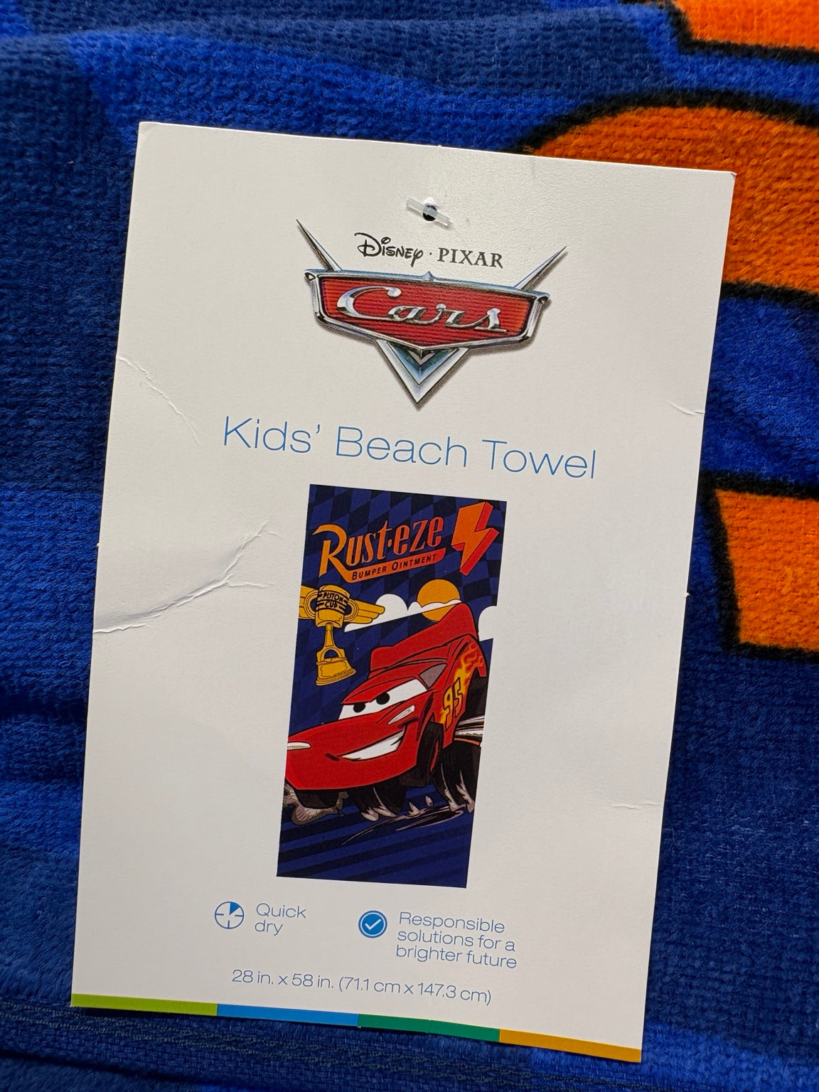 Kids beach towel label showing Lightning McQueen Rust-eze artwork, quick dry and 28 by 58 inch size